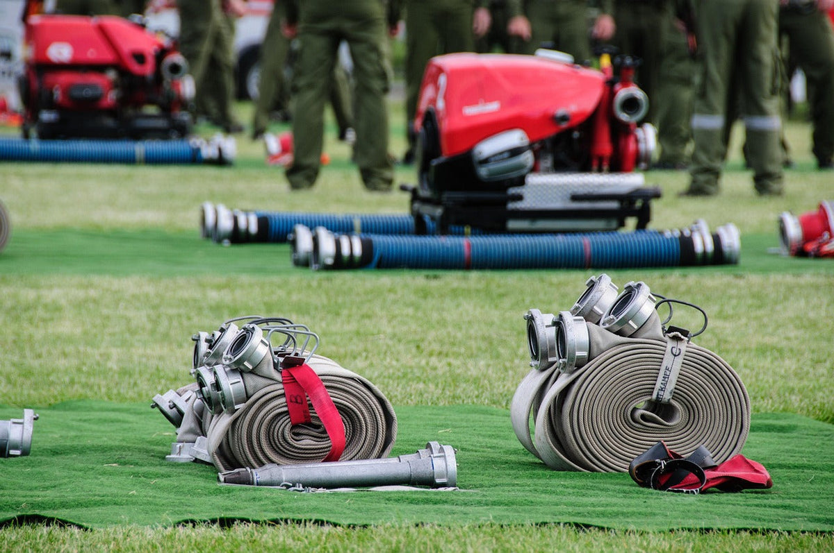 Fire hose and nozzles laid out on grass for maintenance and inspection