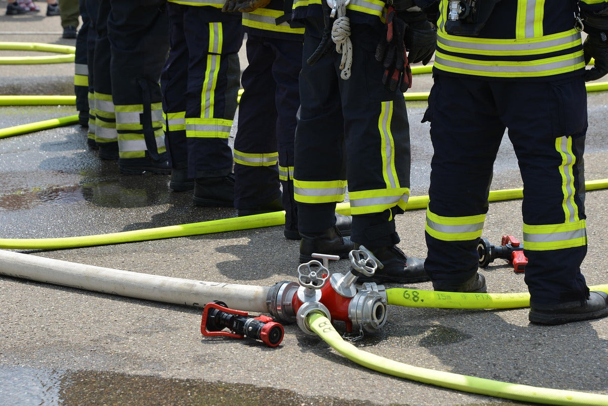 Firefighters in turnout gear advancing yellow fire hose on scene