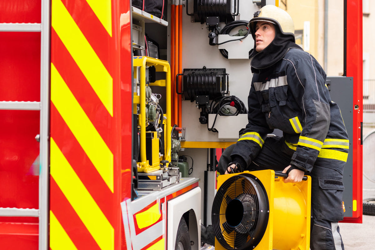 Firefighter unloading a positive pressure ventilation fan from an engine